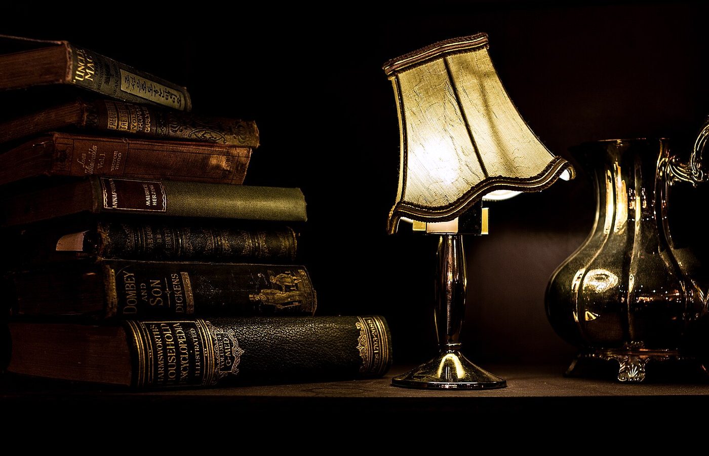 Lampe allumée et vieux livres reliés dans la pénombre