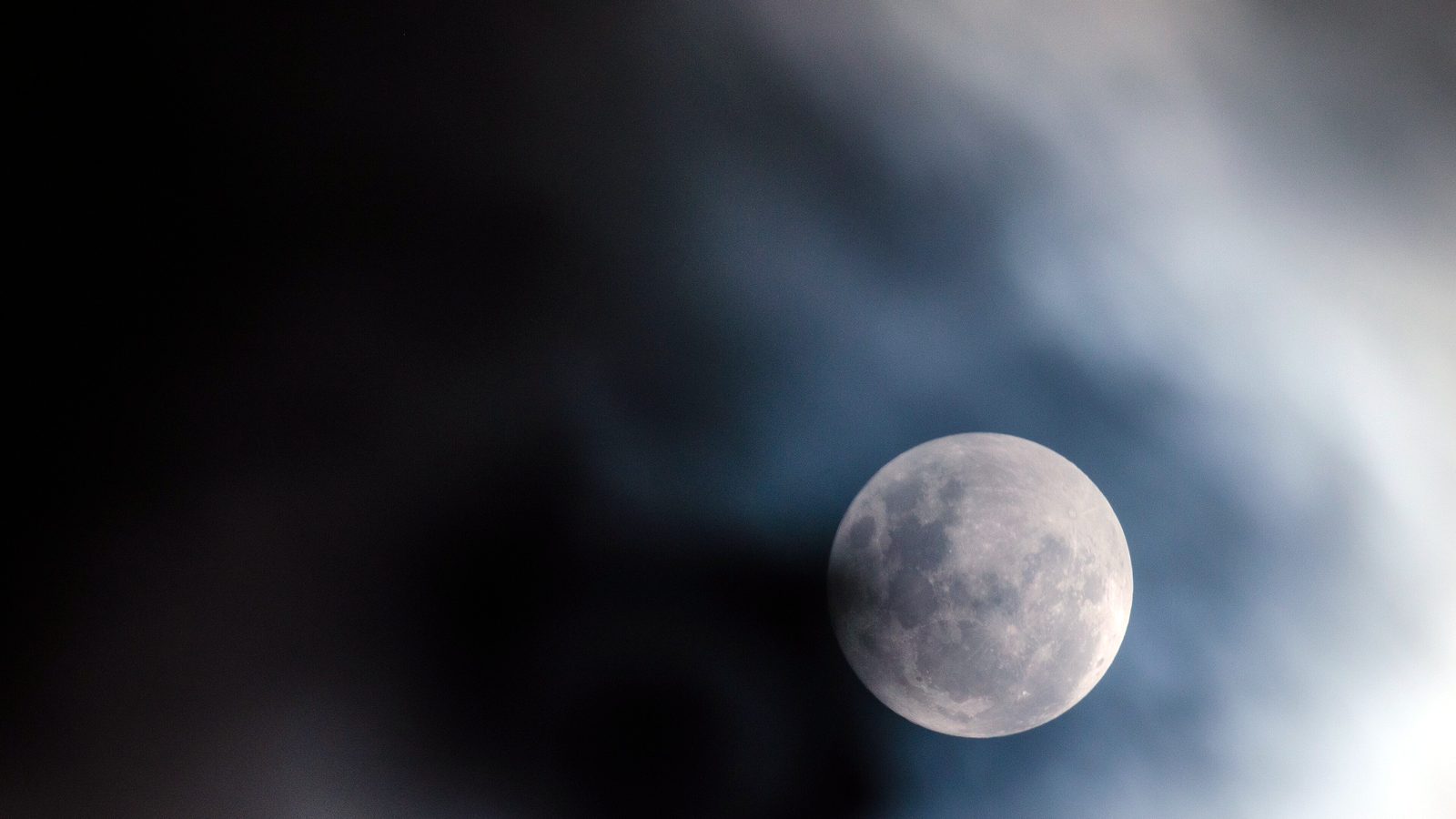 Pleine lune voilée de nuages dans un ciel de nuit